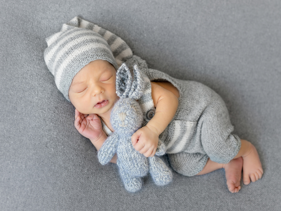 Спящий младенец с серым вязаным зайцем