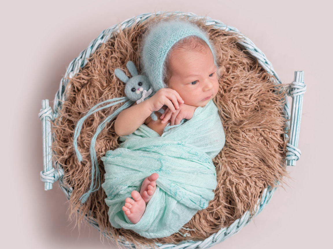 Маленький ребенок в корзине на сером фоне