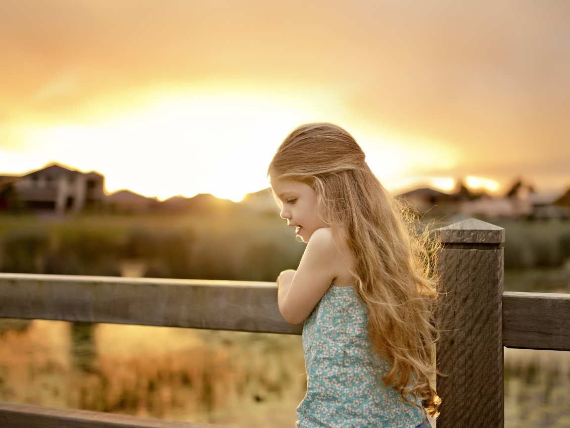 Красивая маленькая девочка на закате солнца