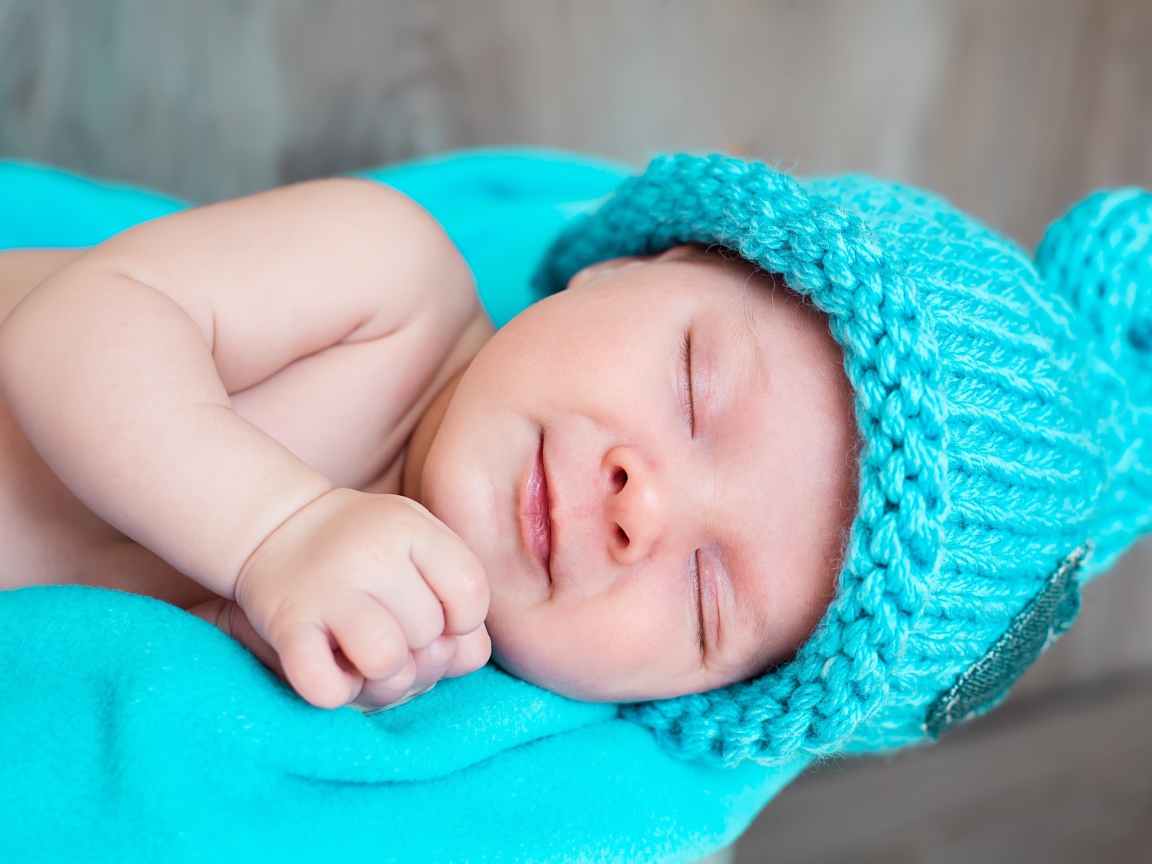 Милый спящий ребенок в голубой вязаной шапке