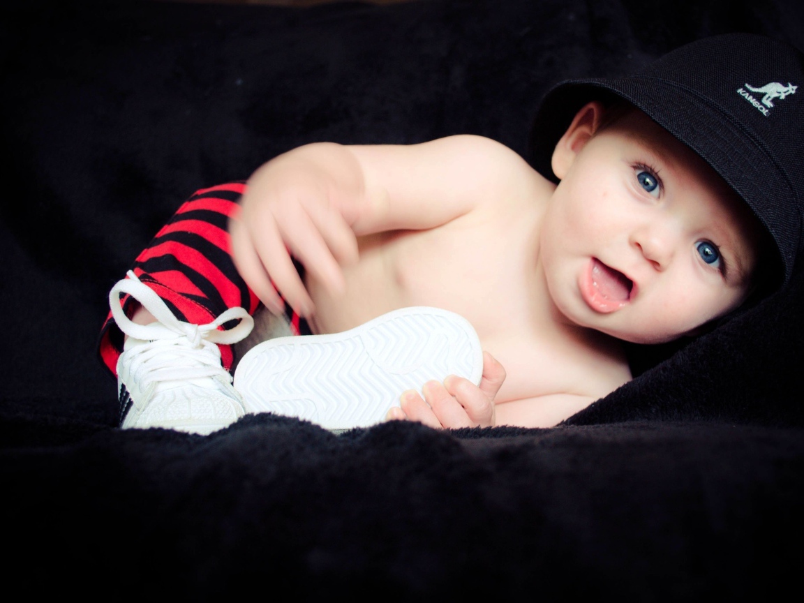 Забавный улыбающийся ребенок в черной панаме