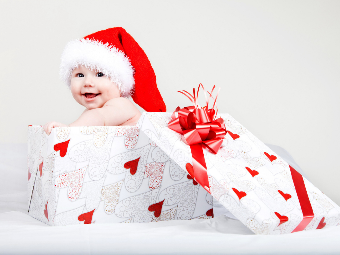Маленький ребенок в новогоднем костюме в коробке для подарка на сером фоне