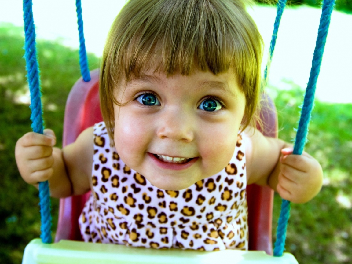Маленькая голубоглазая девочка на качели