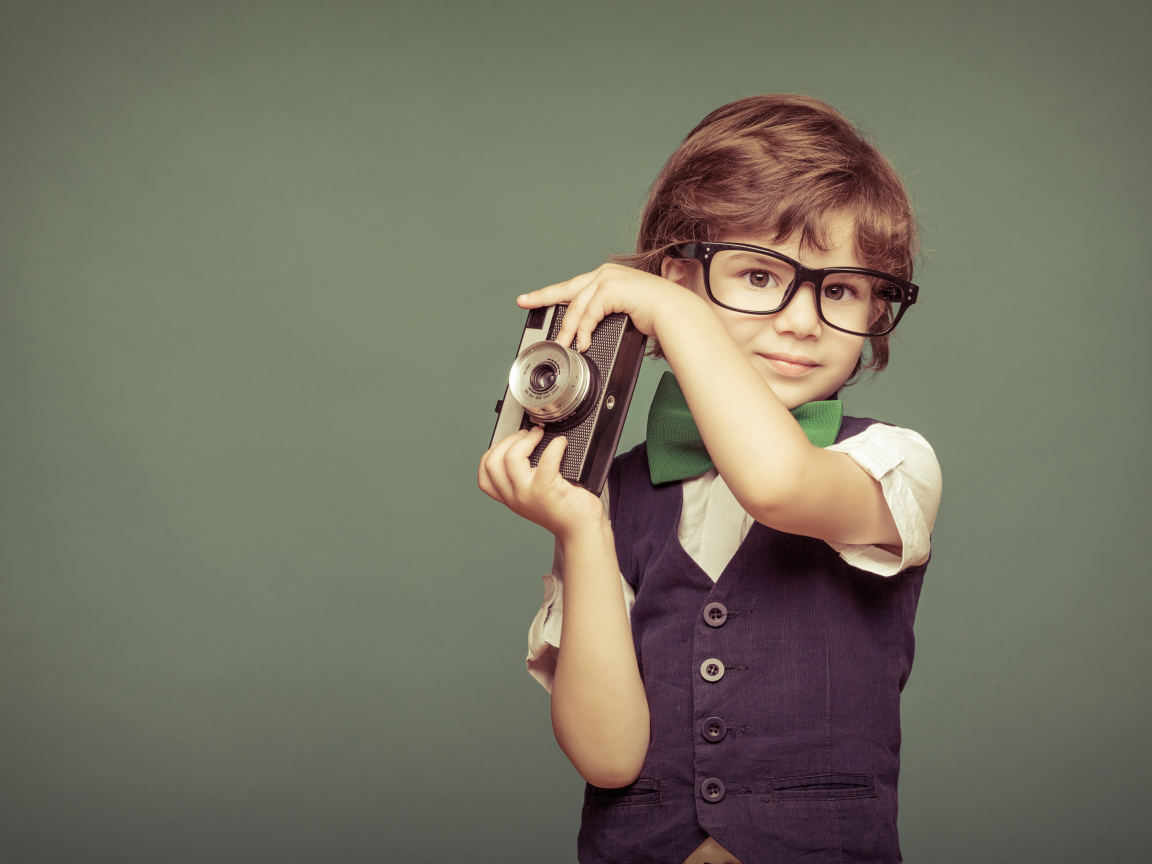 Маленький мальчик в очках с фотоаппаратом