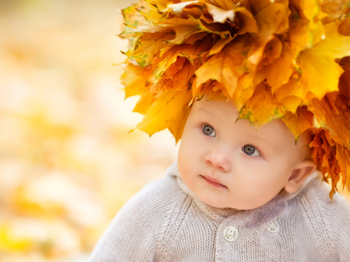 Маленький милый ребенок с венком из желтых листьев на голове 