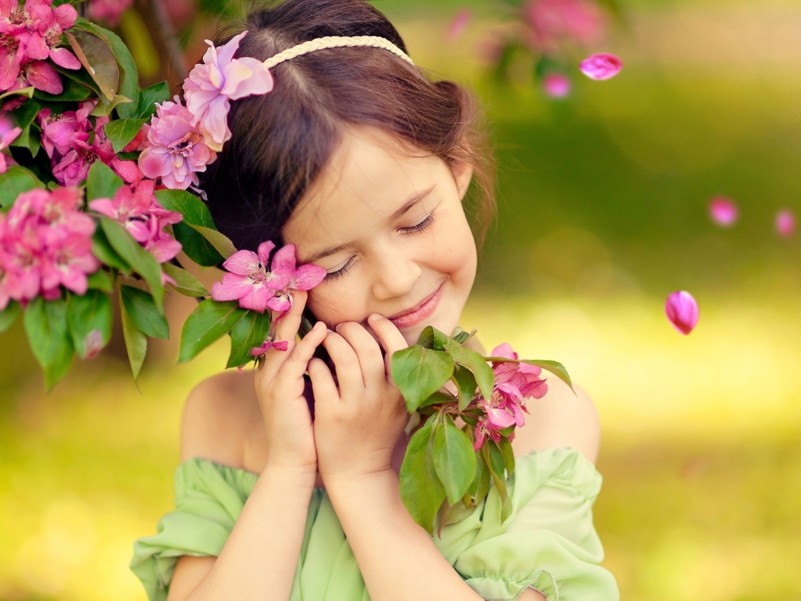 Маленькая девочка обнимает ветку с розовыми цветами