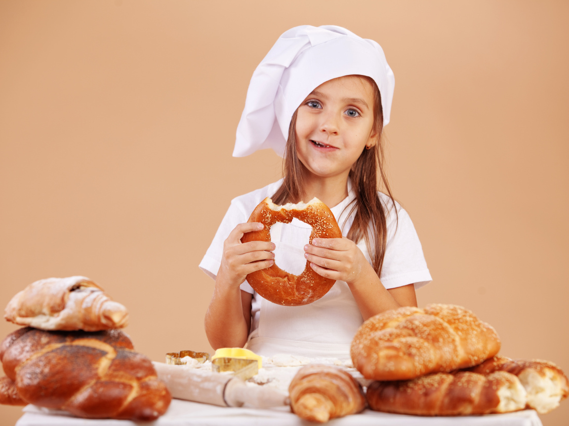 Маленькая девочка в костюме повара и свежей выпечкой