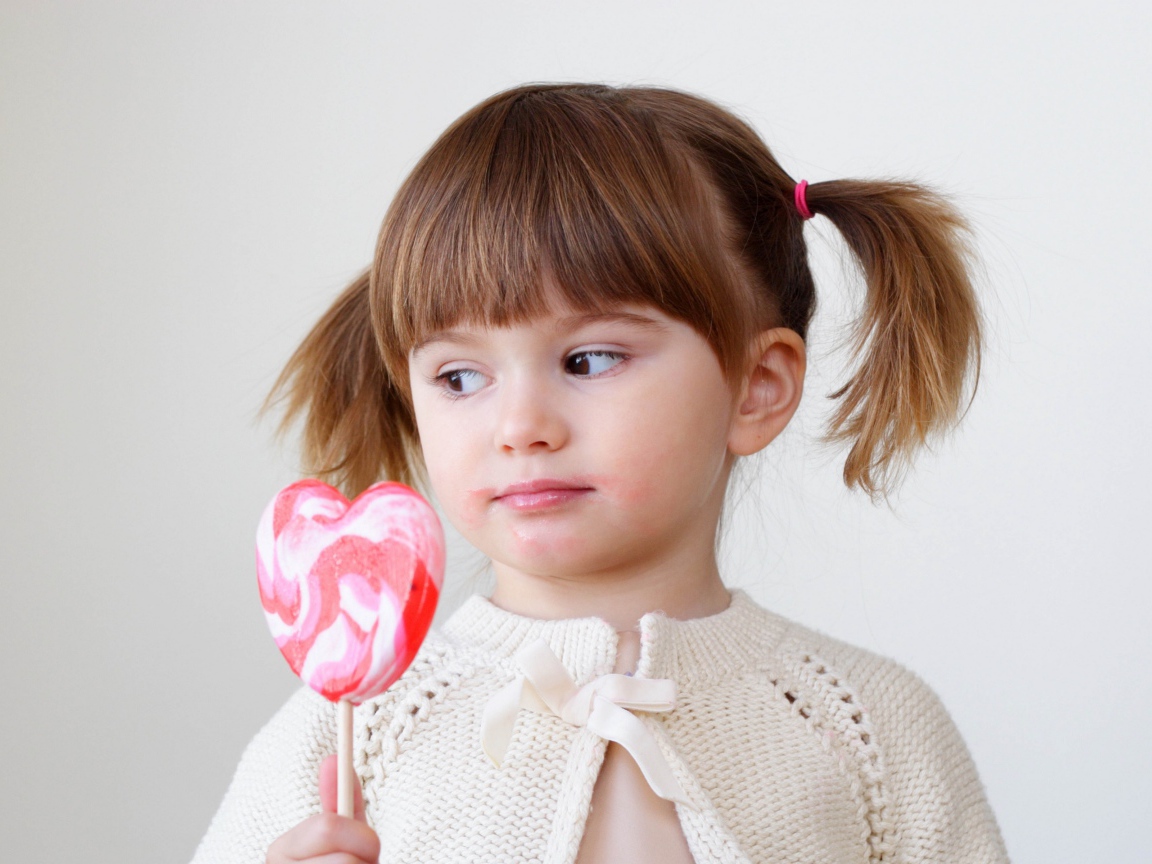 Маленькая девочка с большой конфетой на палочке