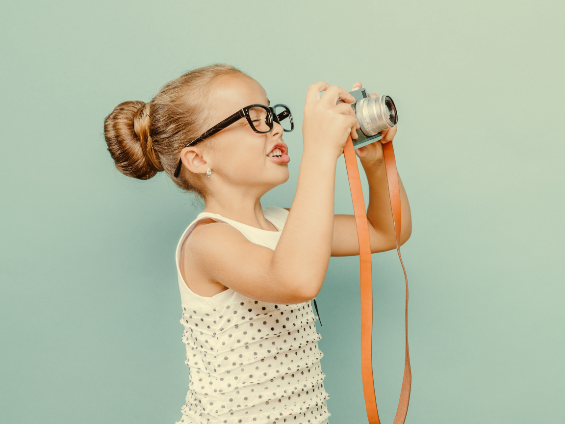 Маленькая девочка в очках с фотоаппаратом