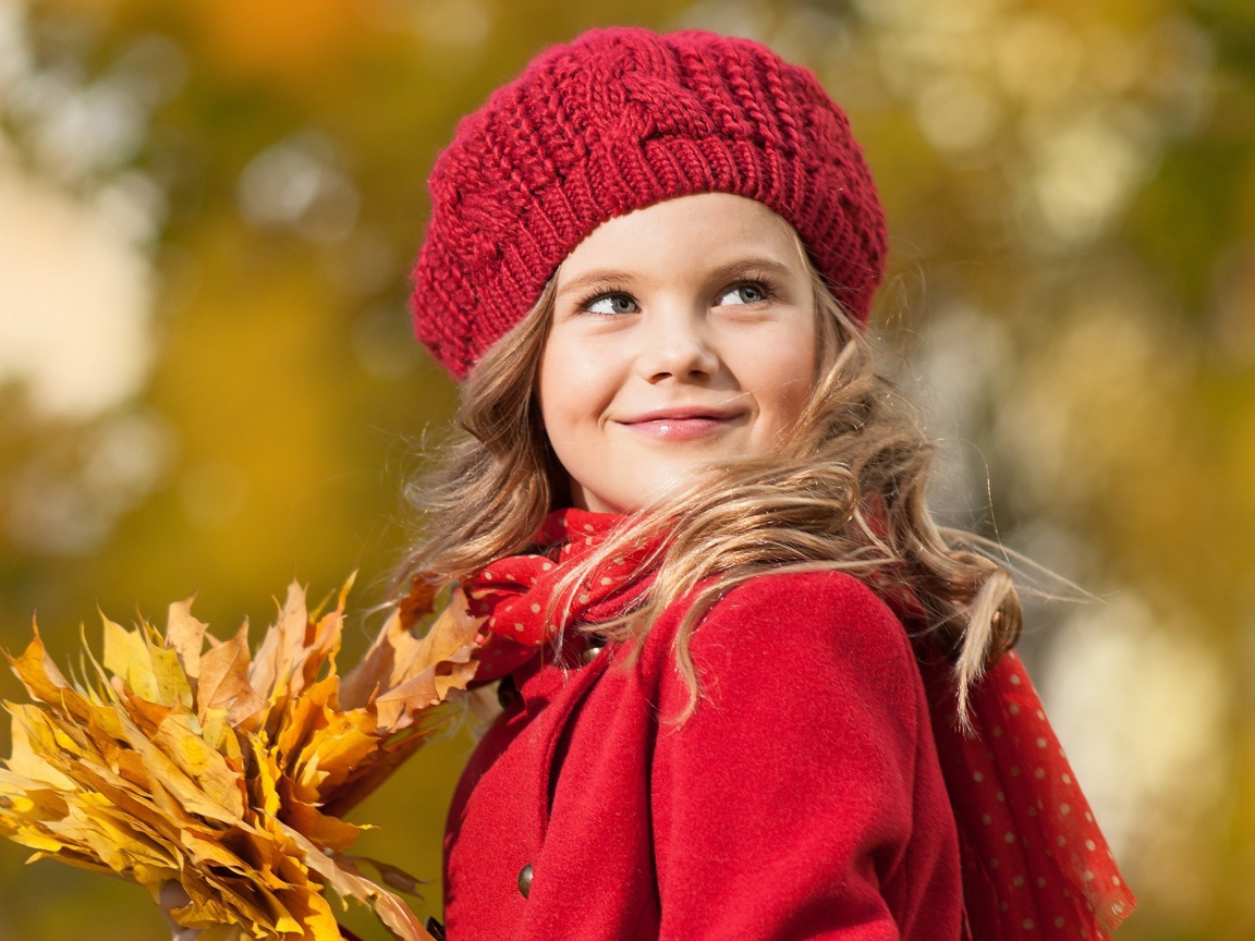 Маленькая девочка с желтыми листьями в руке осенью