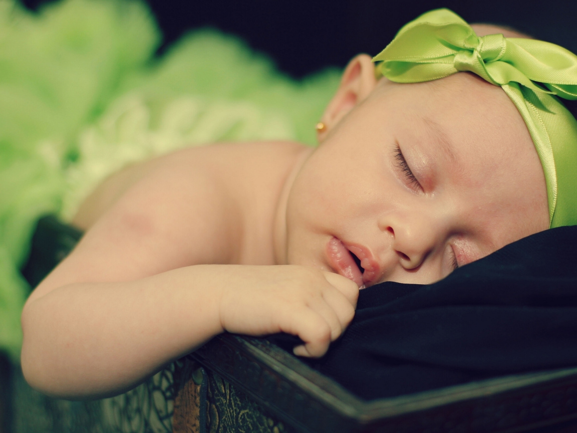 Маленькая спящая девочка с ленточкой на голове