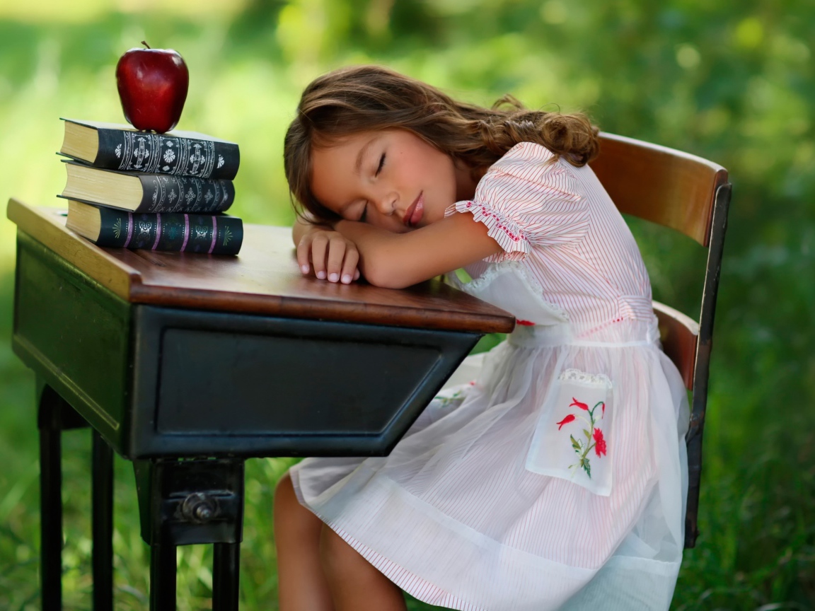 Уставшая маленькая ученица уснула за партой