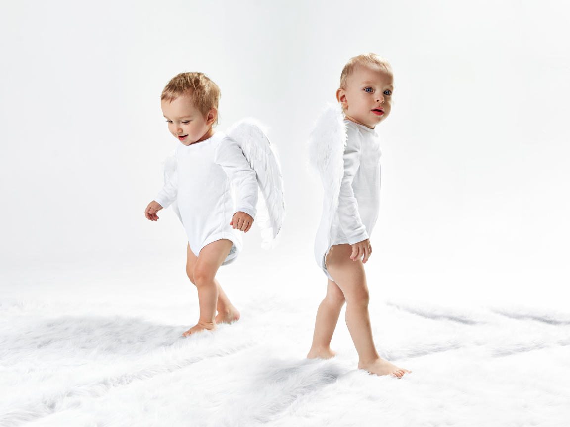 Два маленьких мальчика в костюмах ангела на белом фоне
