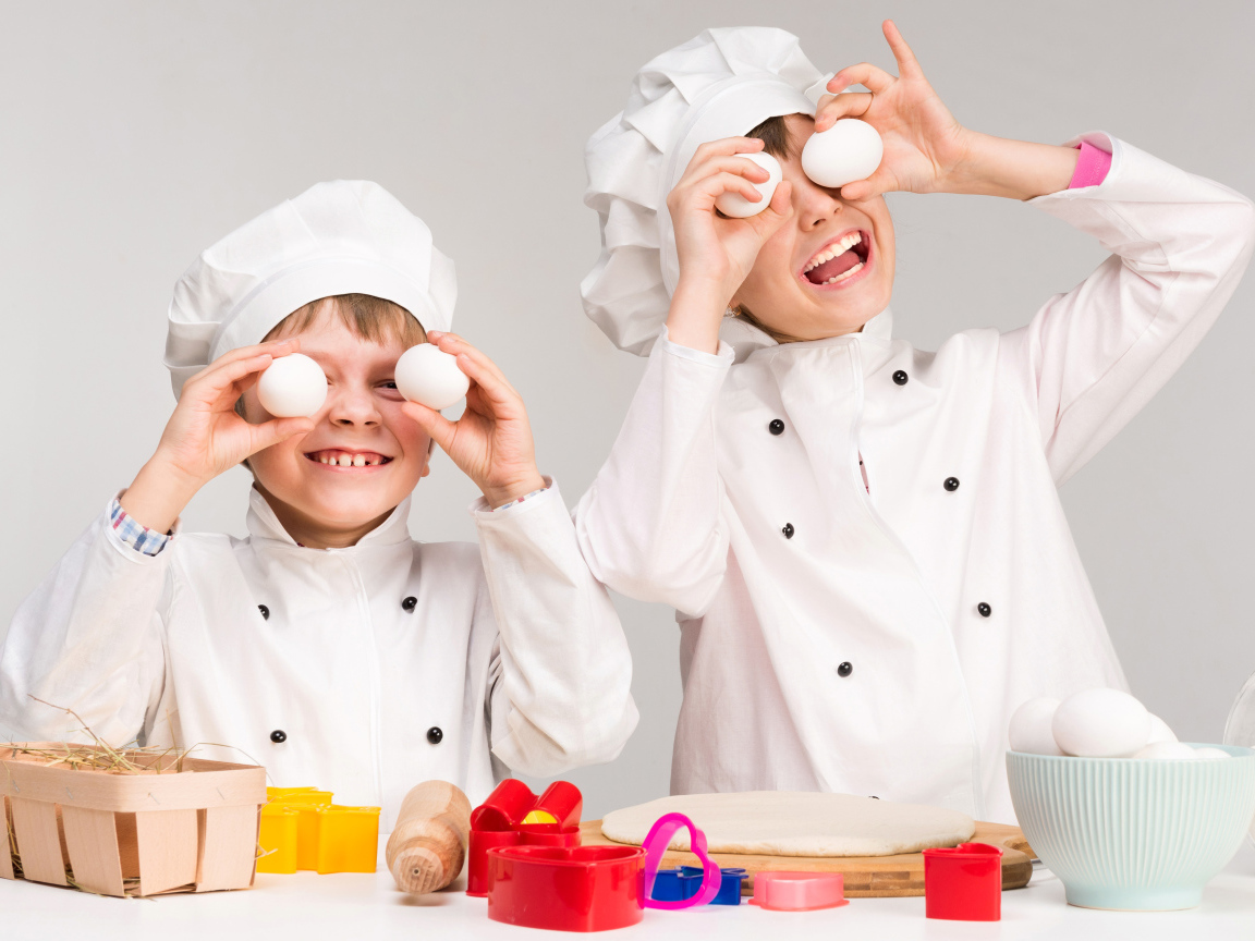 Два маленьких мальчиках в костюмах повара на кухне