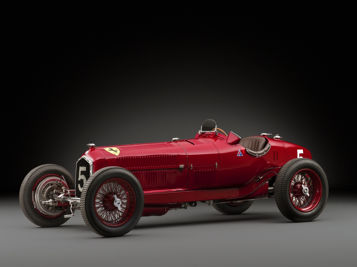 Красный ретро автомобиль Alfa Romeo на сером фоне