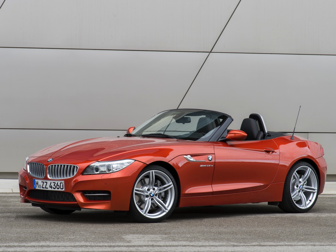 Оранжевый автомобиль кабриолет BMW Z4 на фоне стены