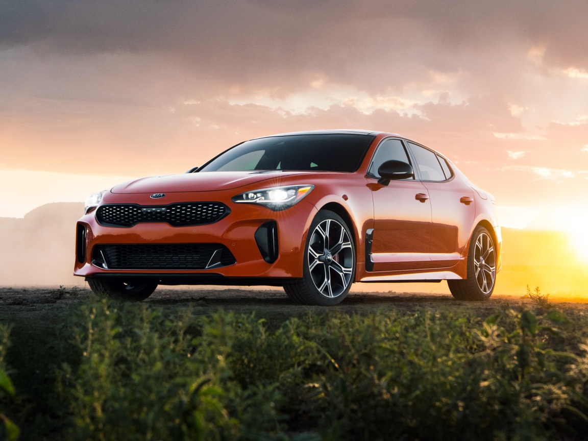 Оранжевый автомобиль  Kia Stinger GTS, 2020 года на закате