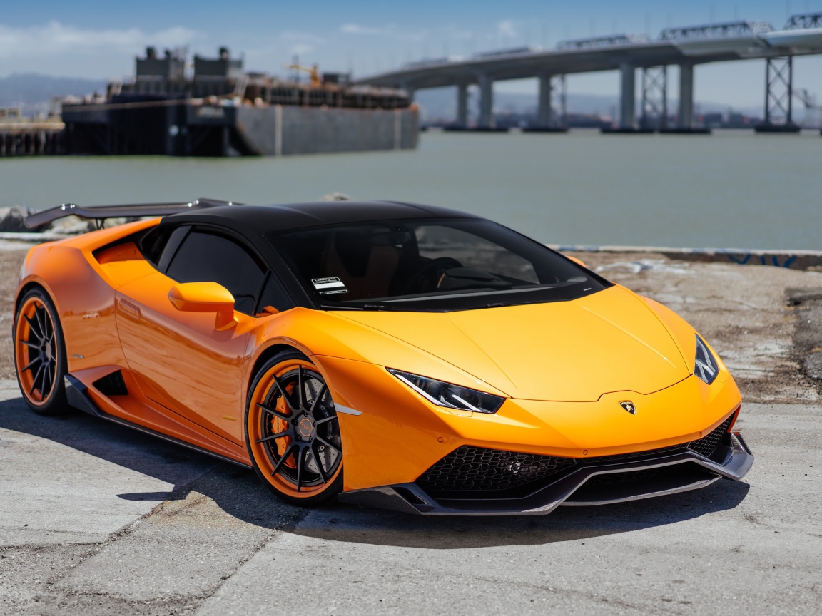 Оранжевый быстрый Lamborghini Huracan в порту у воды