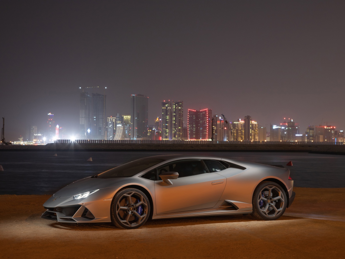 Серебристый автомобиль Lamborghini Huracan Evo на фоне города