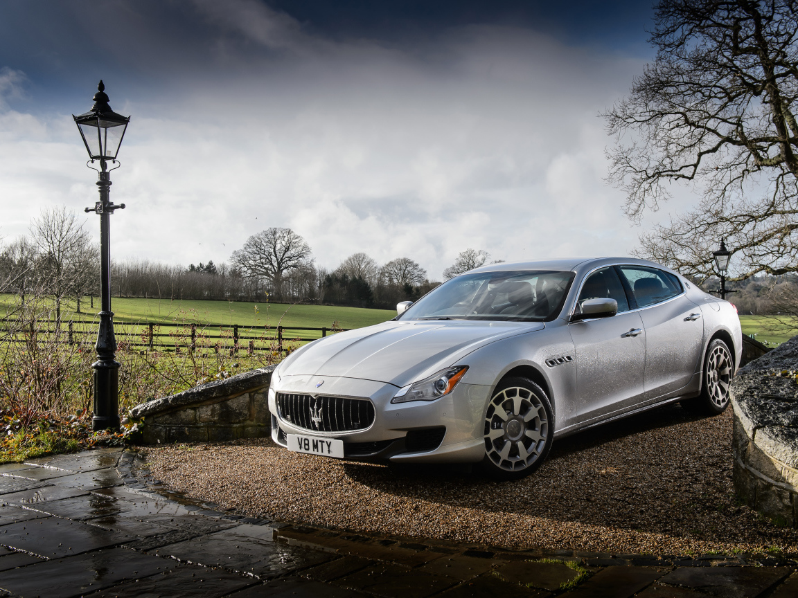 Серебристый стильный дорогой автомобиль Maserati Quattroporte на дороге после дождя