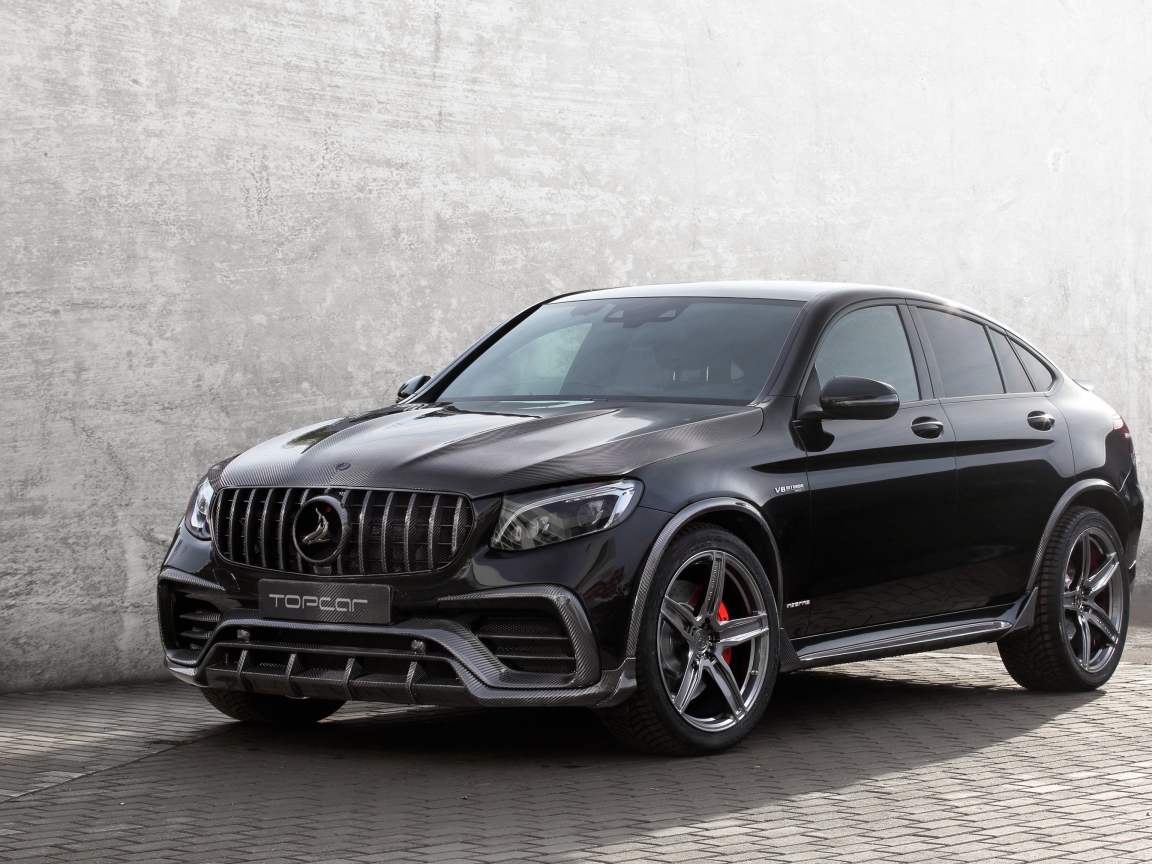 Черный автомобиль Mercedes-AMG GLC 63 на фоне серой стены 