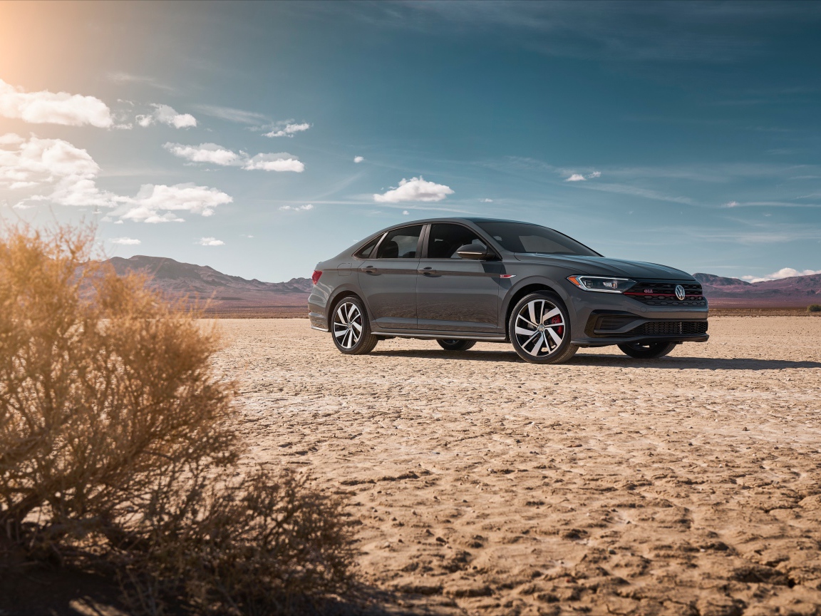 Стильный серебристый автомобиль Volkswagen Jetta на фоне неба 