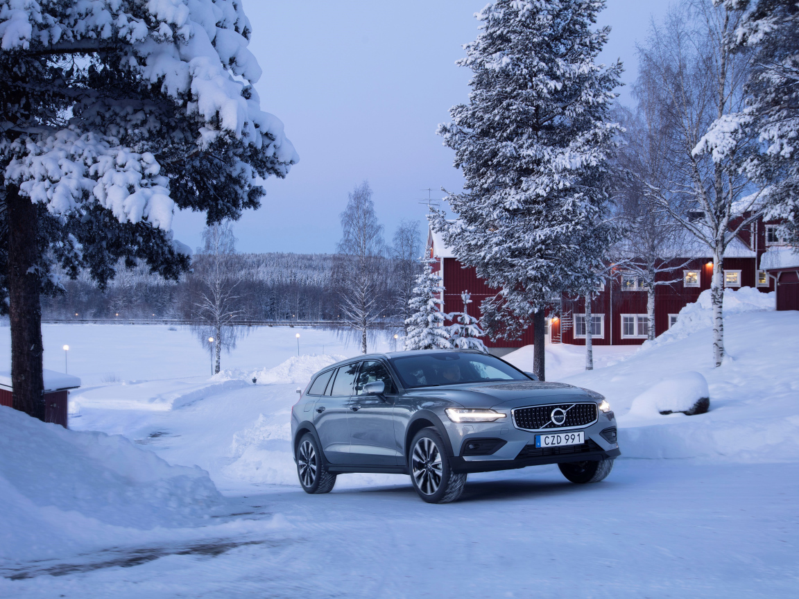 Автомобиль Volvo V60 на фоне заснеженных деревьев 
