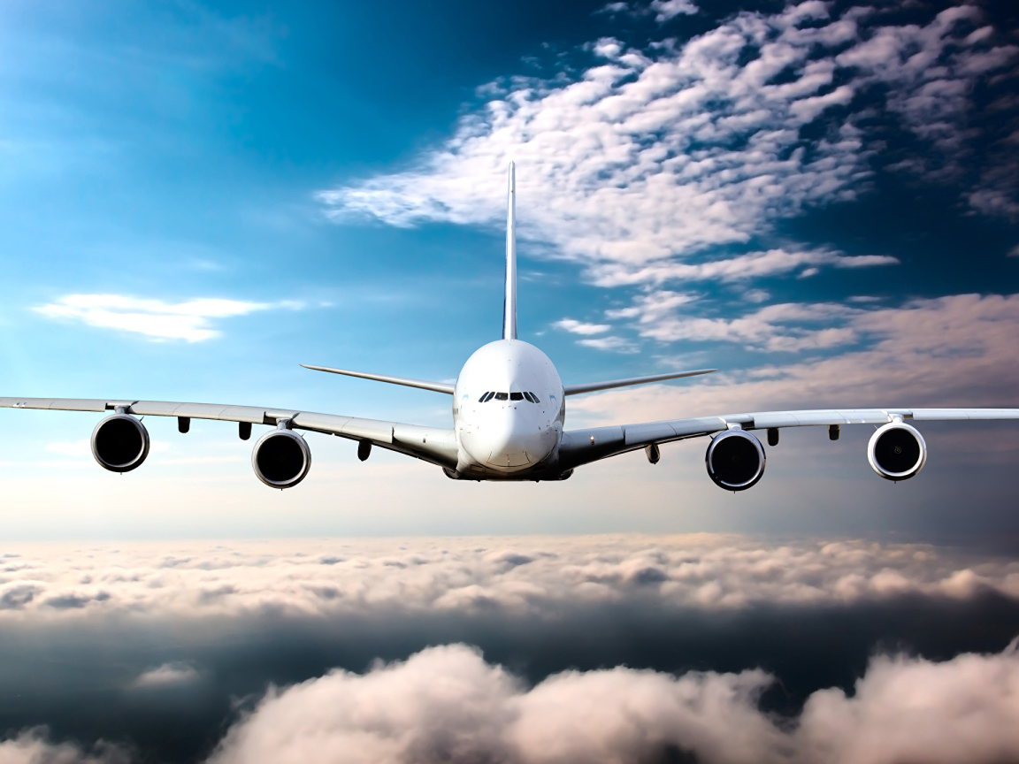 Самолет в белых облаках на фоне голубого неба