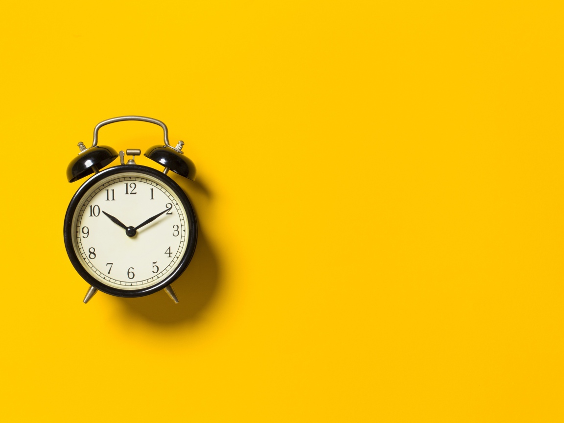 Черный будильник на желтом фоне