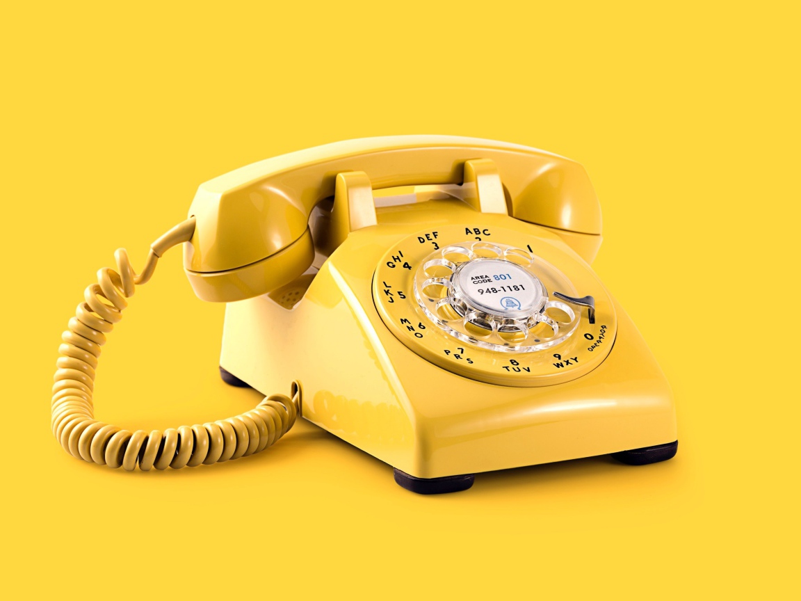 Старый желтый телефон на желтом фоне
