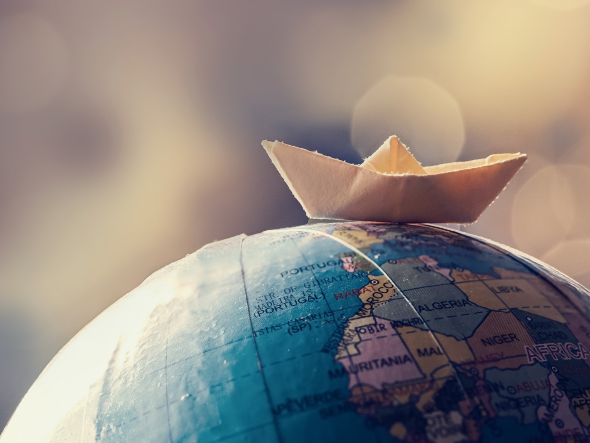 Бумажный кораблик лежит на глобусе