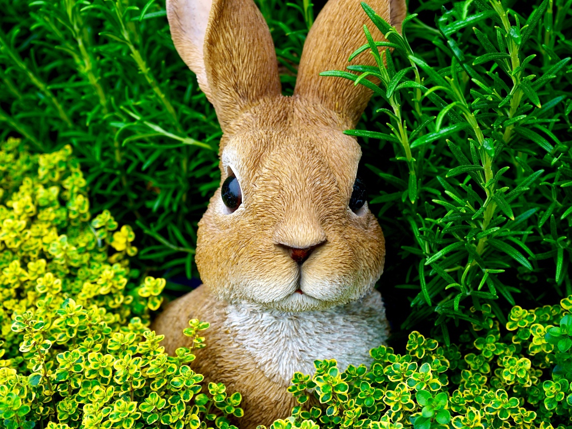 Статуэтка кролика в зеленой траве 