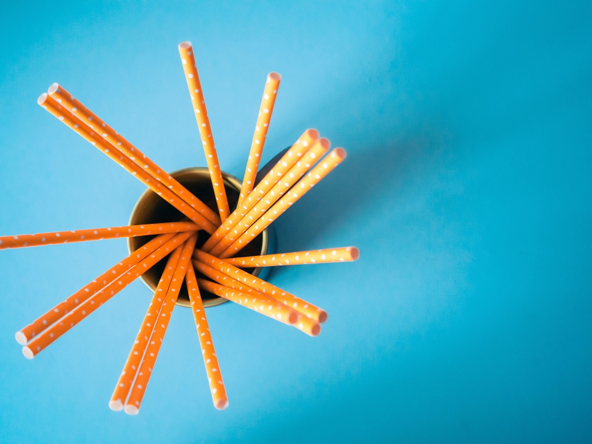 Трубочки в стакане на голубом столе