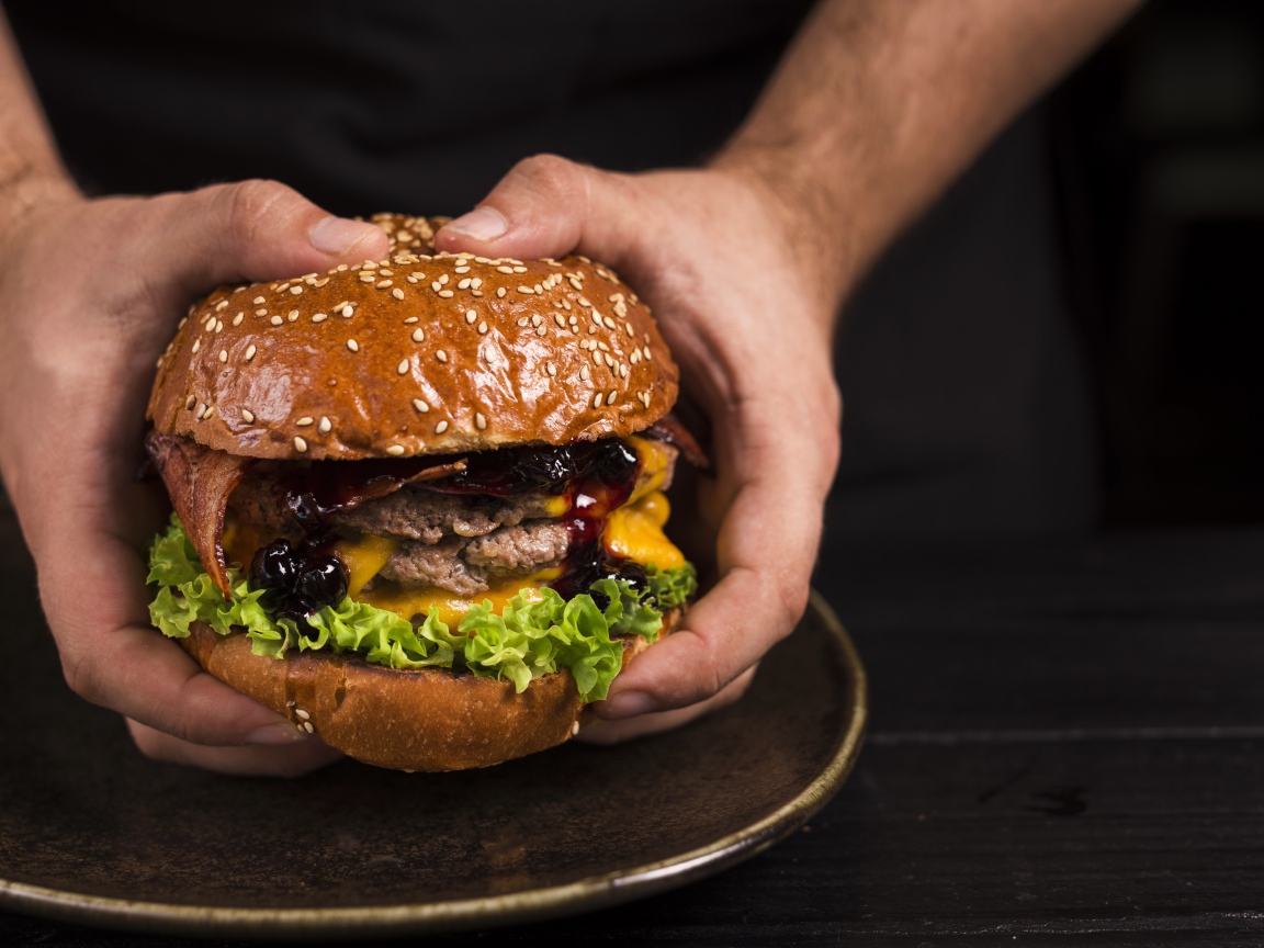 Большой сочный гамбургер в руках