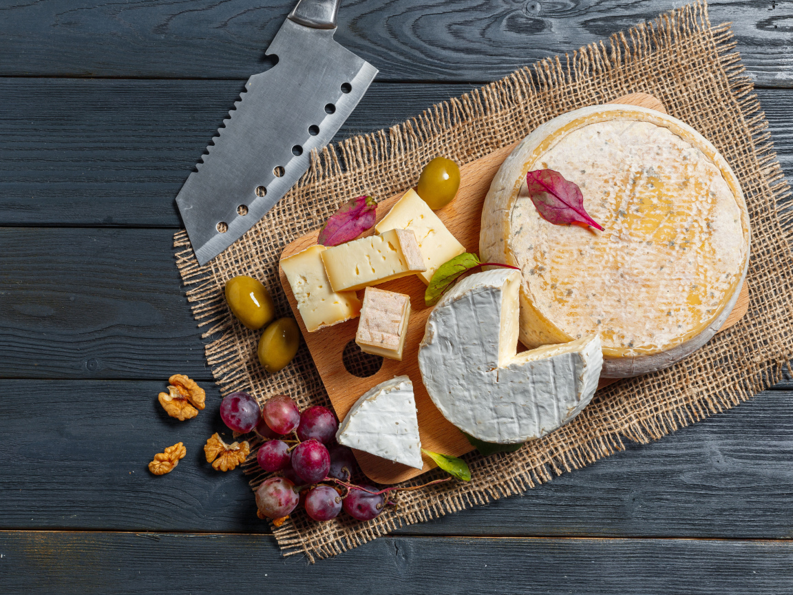 Сыр с плесенью на столе с орехами и виноградом 