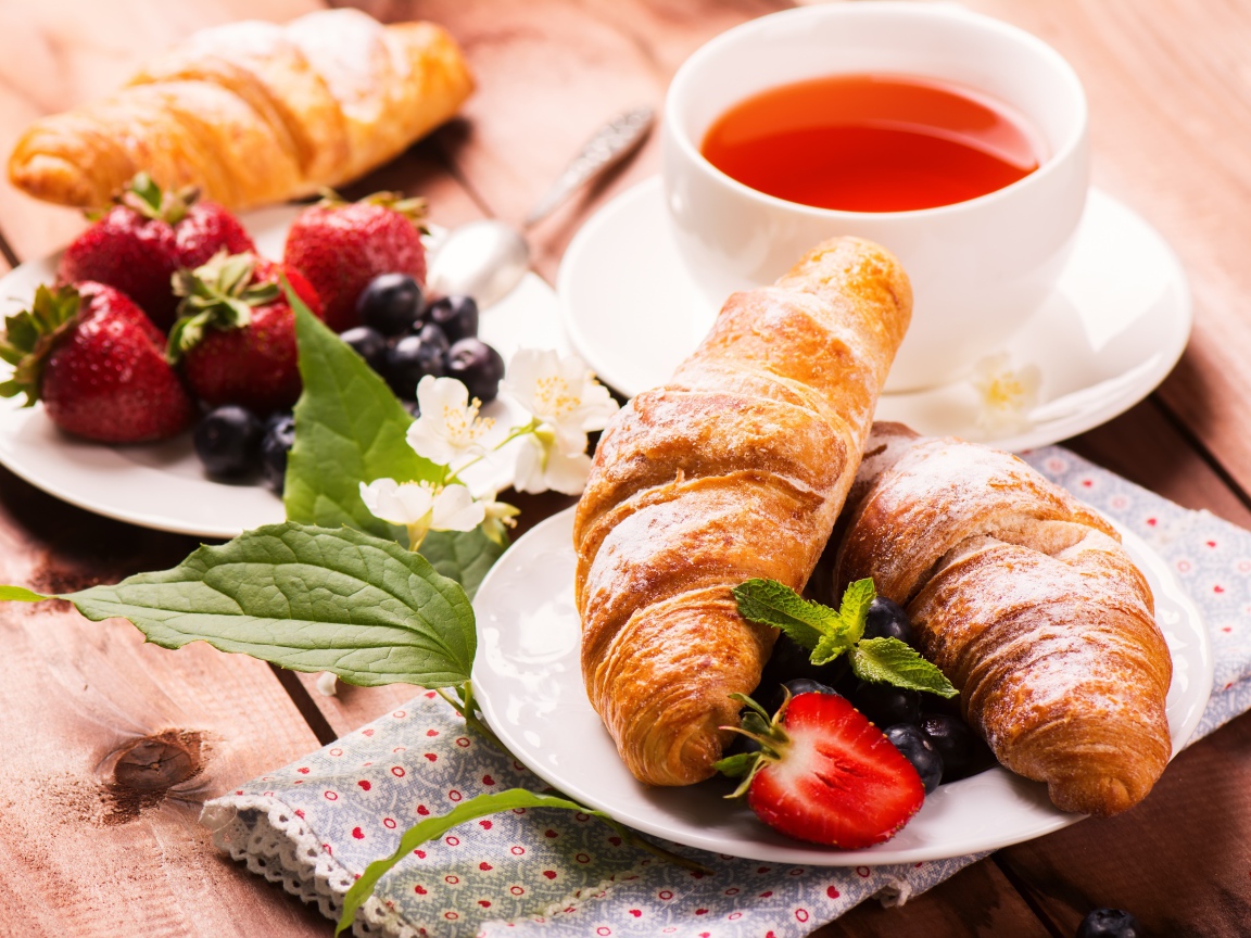 Круассаны на столе с ягодами и чашкой чая