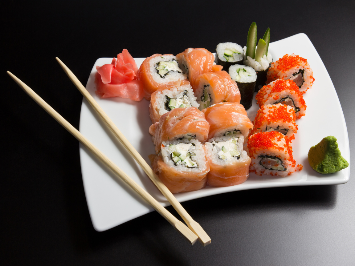 Вкусные японские суши на белой тарелке с палочками