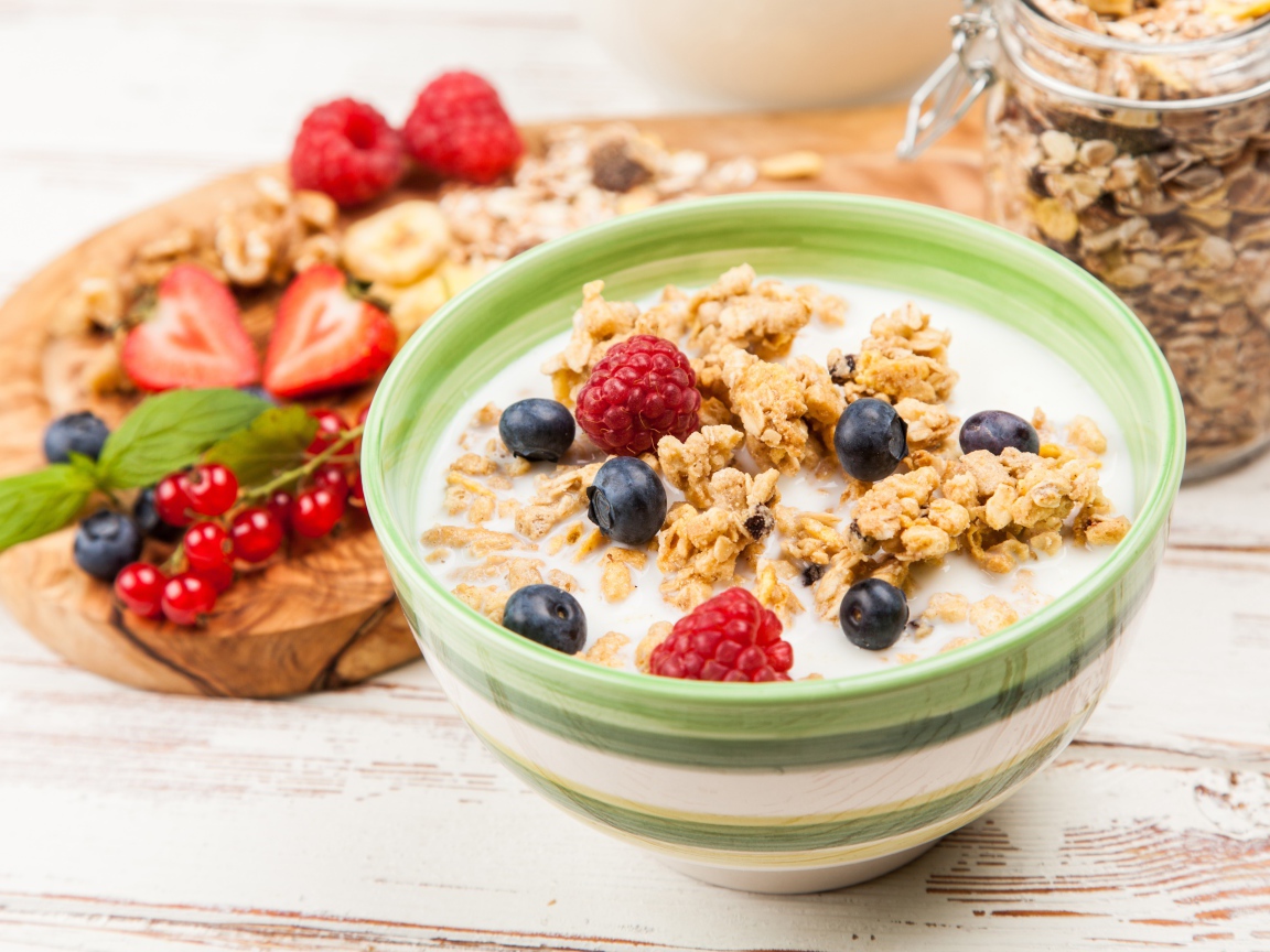 Мюсли с молоком и ягодами на столе к завтраку