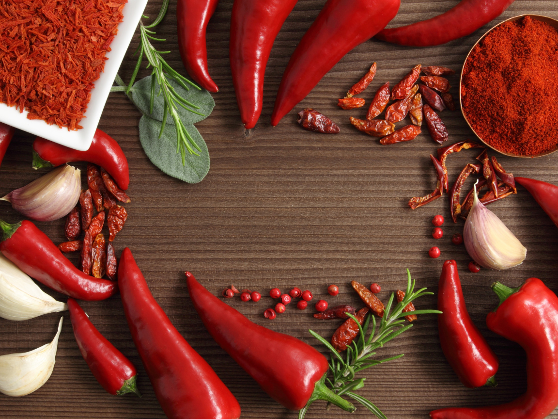 Красный перец с чесноком на деревянном столе