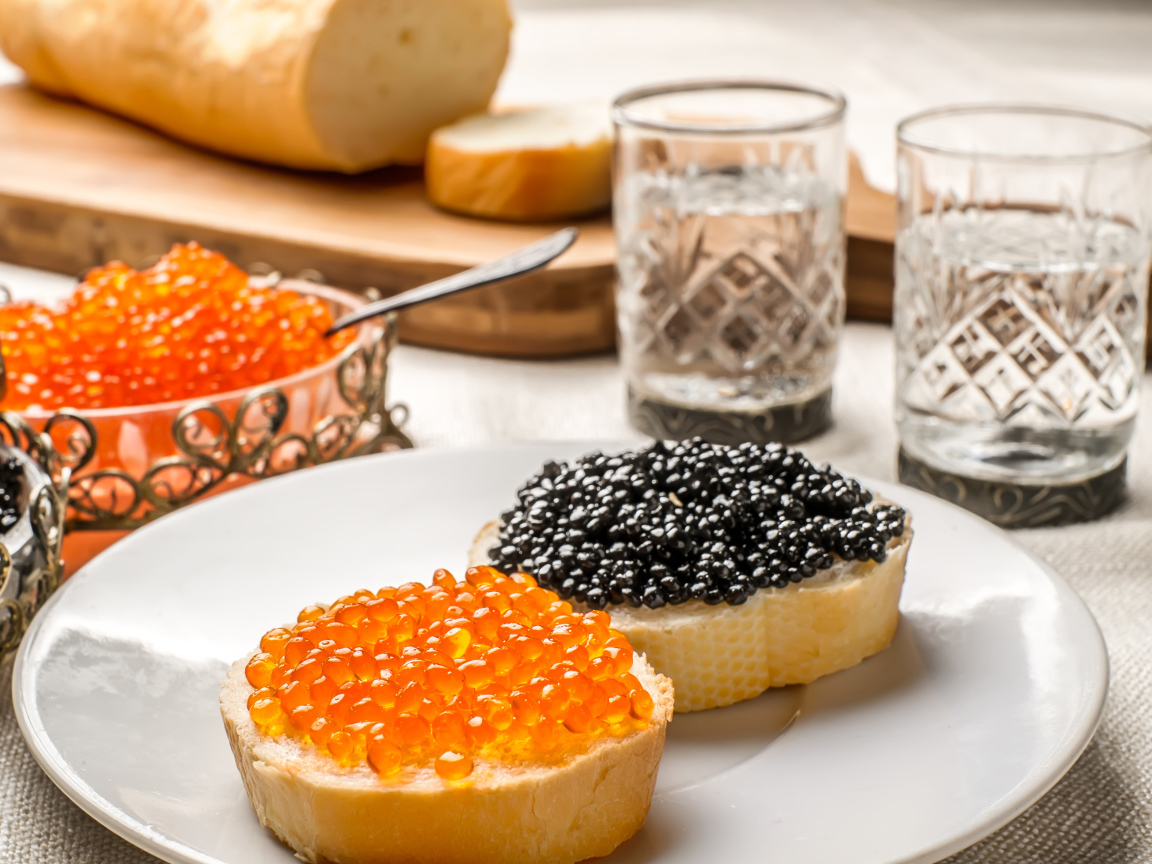 Бутерброды с красной и черной икрой на столе с водкой