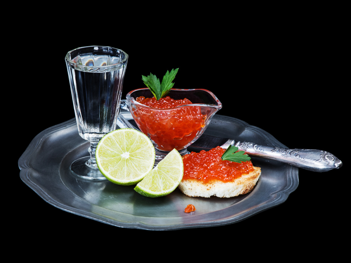 Бутерброды с красной икрой на подносе с рюмкой водки и лаймом
