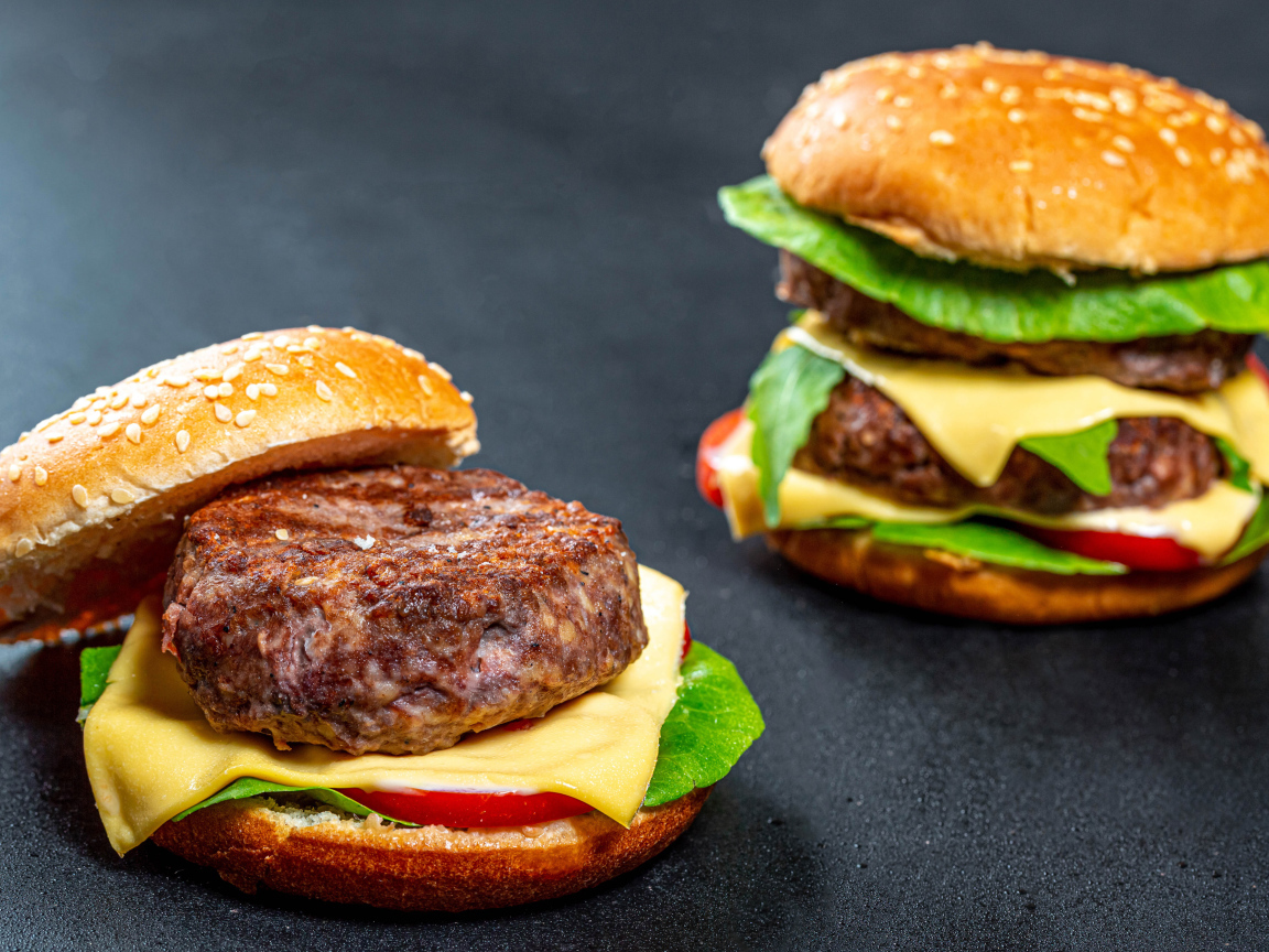 Два гамбургера с большой котлетой на столе