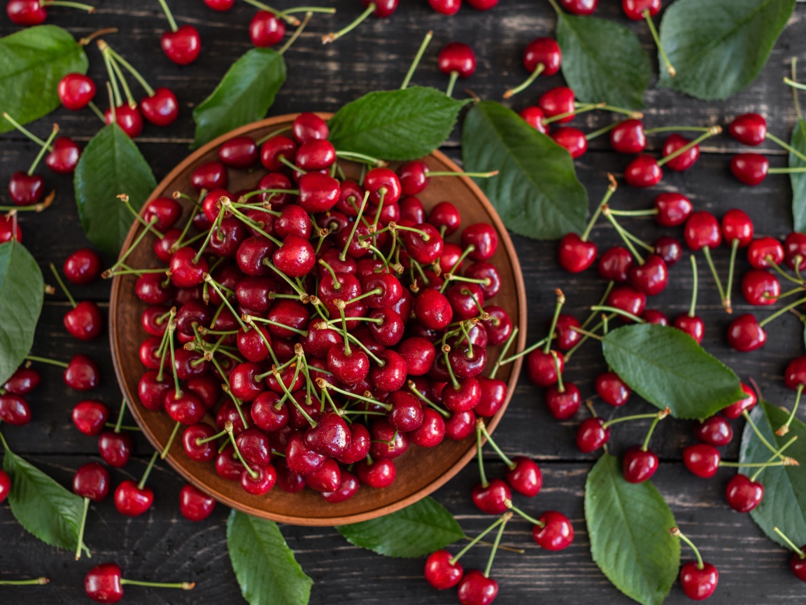 Много спелой красной черешне в миске на столе