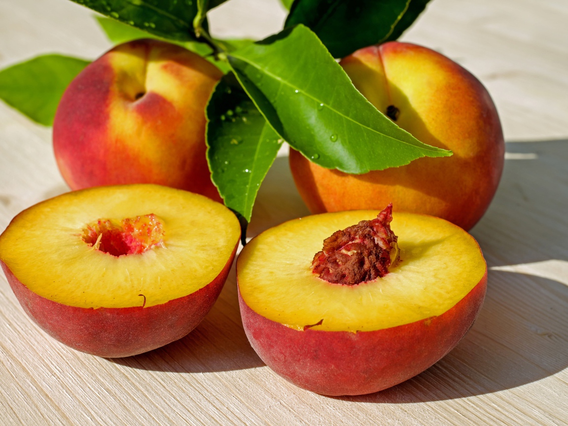 Сочные плоды нектарина с зелеными листьями на столе