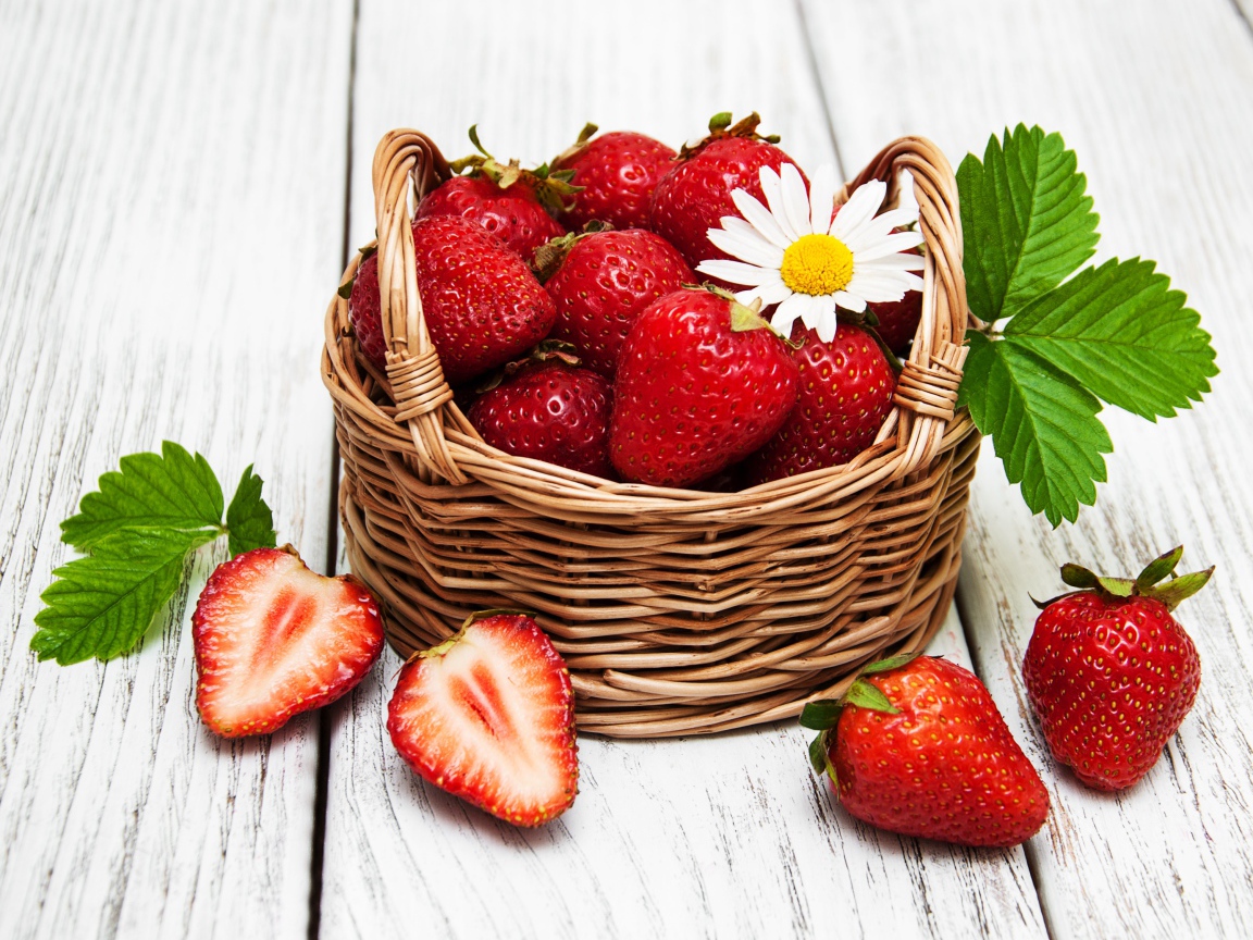 Плетеная корзинка с клубникой, ромашкой и зелеными листьями