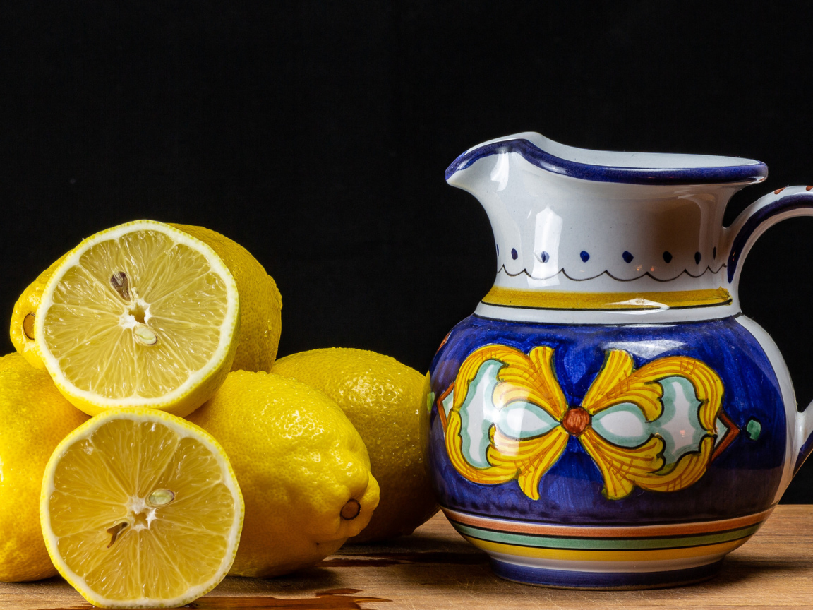 Желтые лимоны на столе с кувшином
