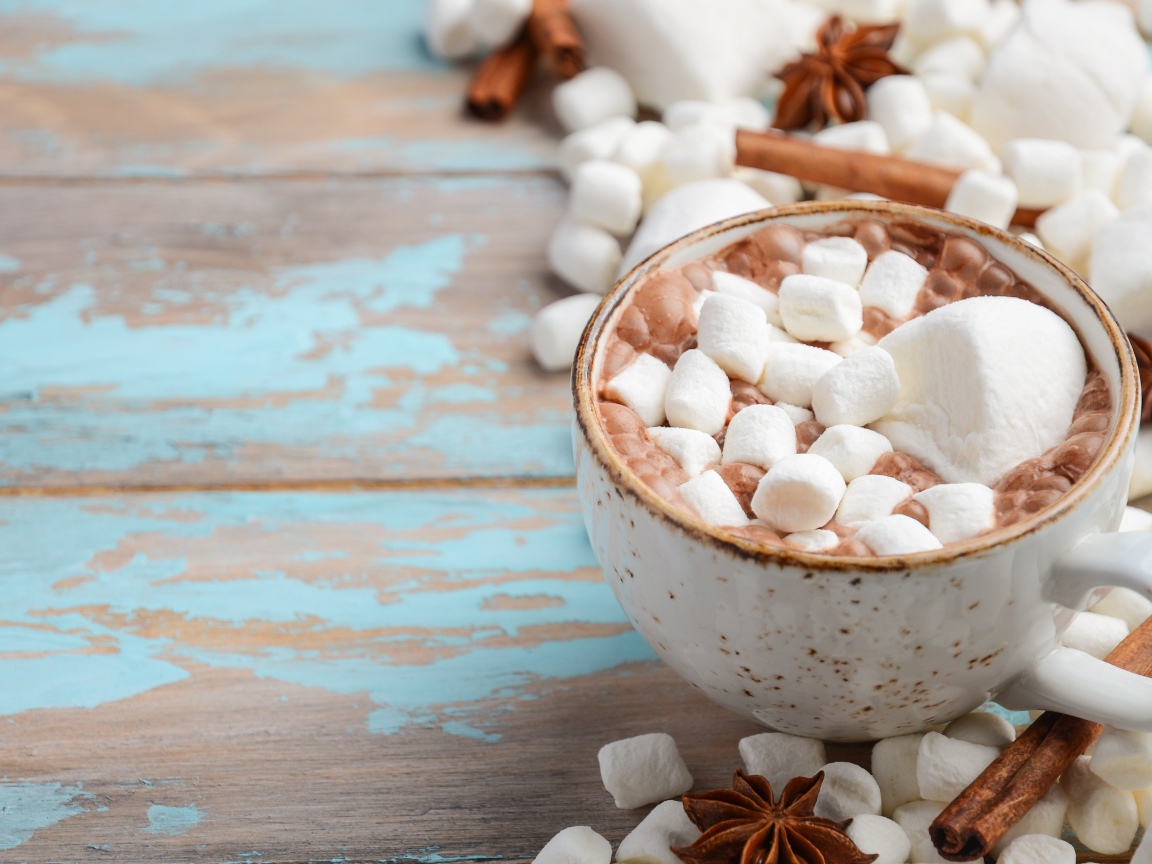 Чашка какао с маршмеллоу на столе с корицей и сладостями