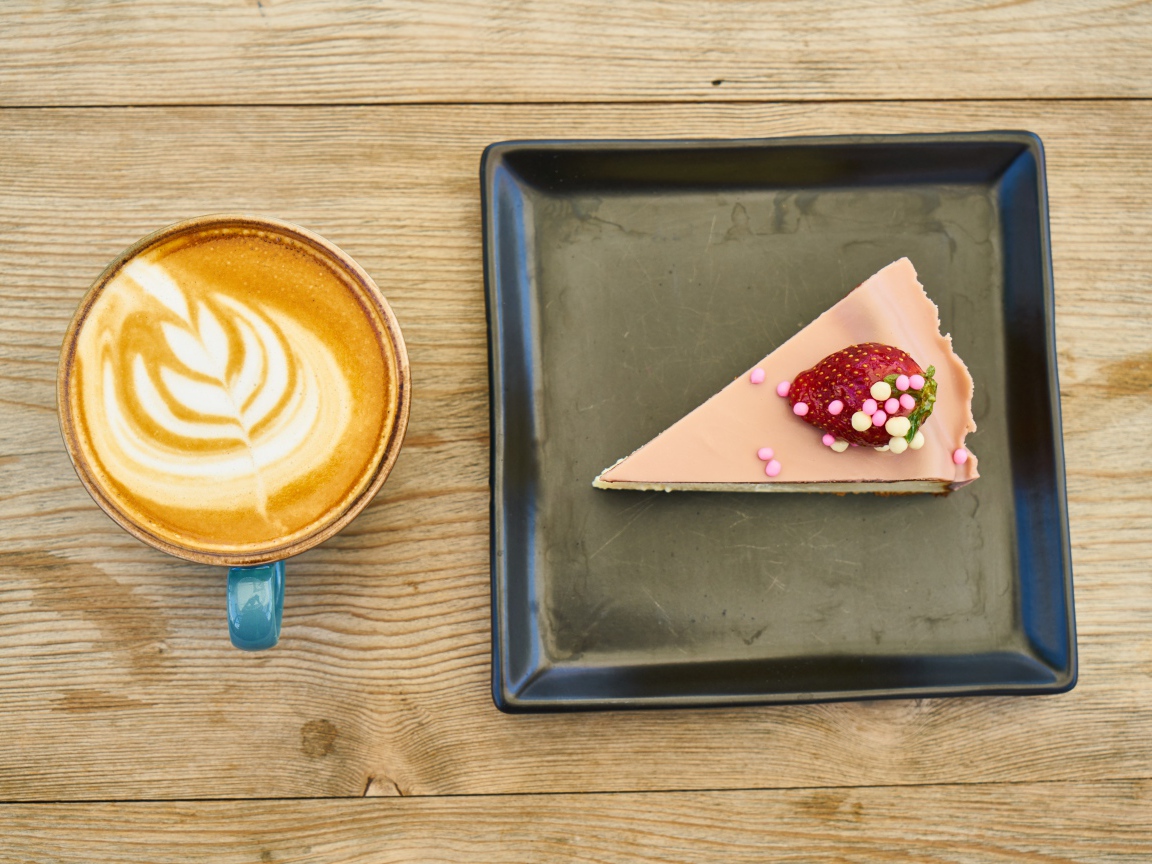 Кусок торта на черной тарелке с кофе