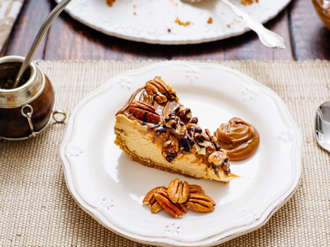 A piece of cake with nuts on a white plate on the table with coffee