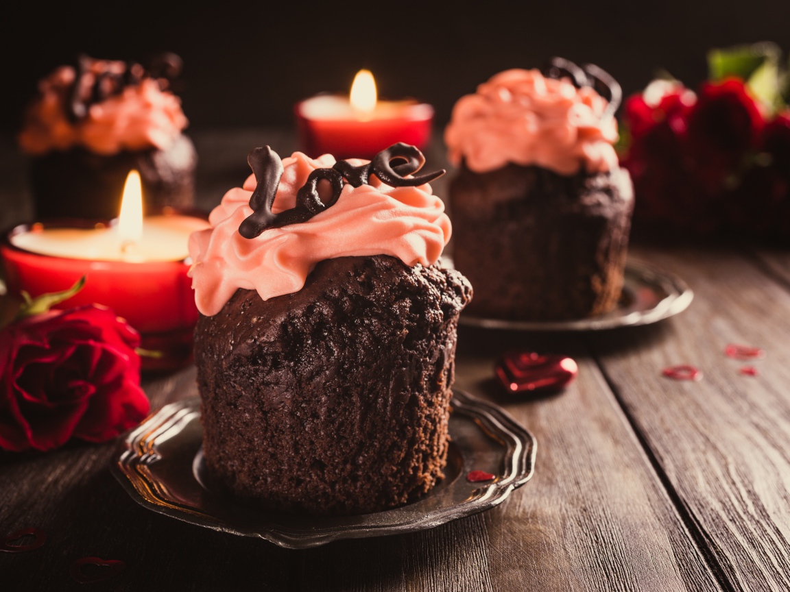 Шоколадные кексы с кремом на столе со свечами и розами